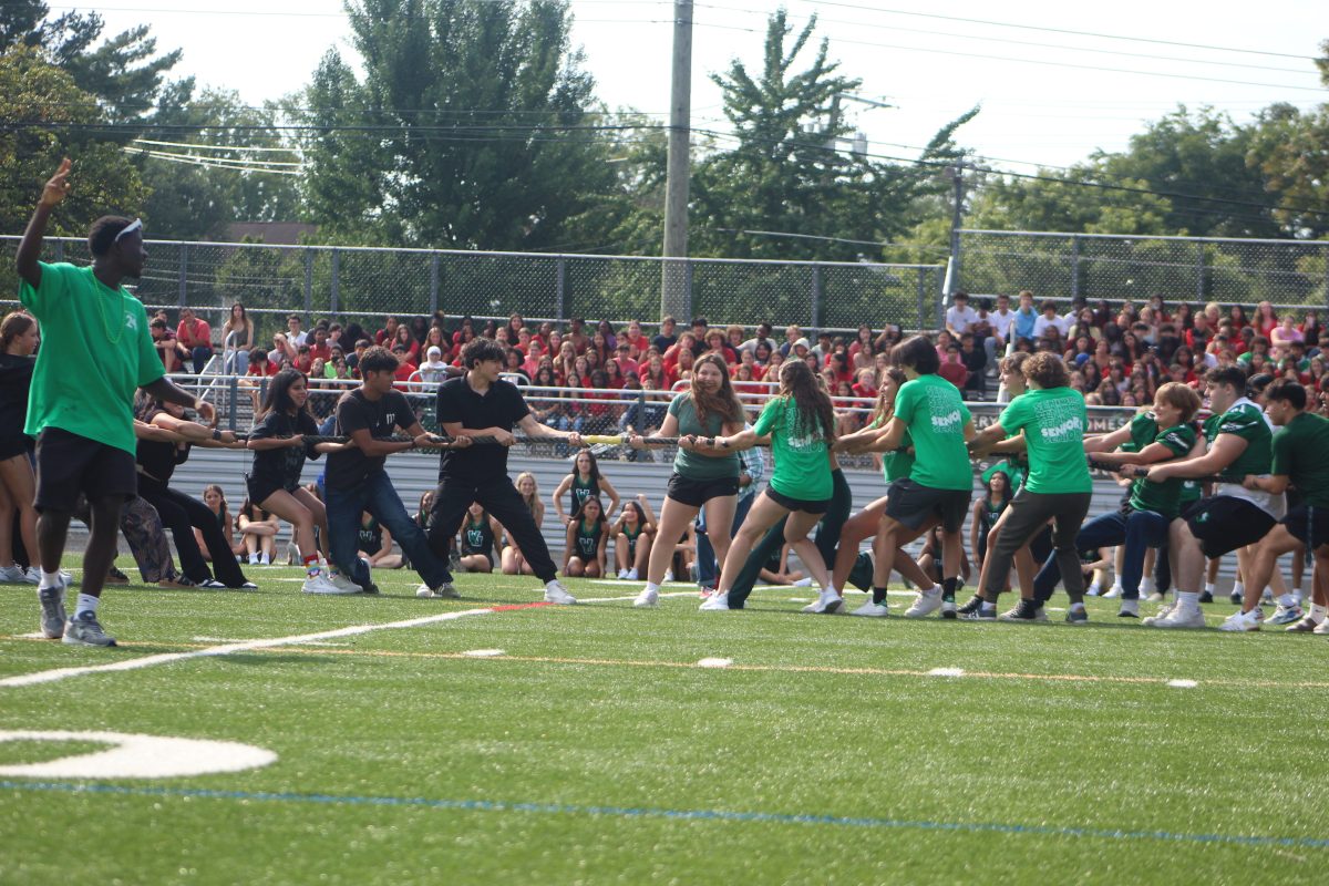 Freshmen+watch+in+the+distance+as+the+juniors+and+seniors+face+off+on+the+50-yard+line+in+the+annual+tug-of-war.+The+seniors+overpowered+the+juniors+on-route+to+winning+the+whole+tournament.