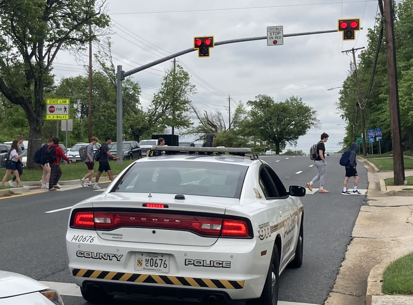 A Montgomery County Police Department police car stands stopped on Democracy Boulevard as WJ students cross. MCPD has dealt with a large spike in the number of school-related security incidents, including a student with a loaded gun at WJ on Oct. 23