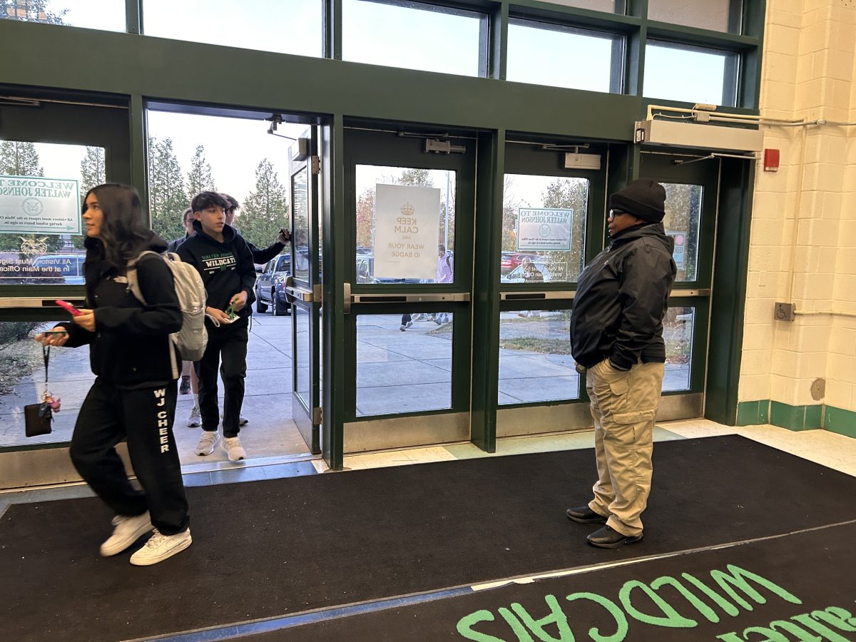 A security guard checks students IDs at the athletic circle entrance on Friday, Nov. 3. Students often quickly flash their IDs to get in, meaning anyone with a backpack and a green ID would likely be let in by security. Students who forget their ID also find it easy to sneak back into school, meaning people who dont belong in the school wouldnt have difficulty sneaking in either.