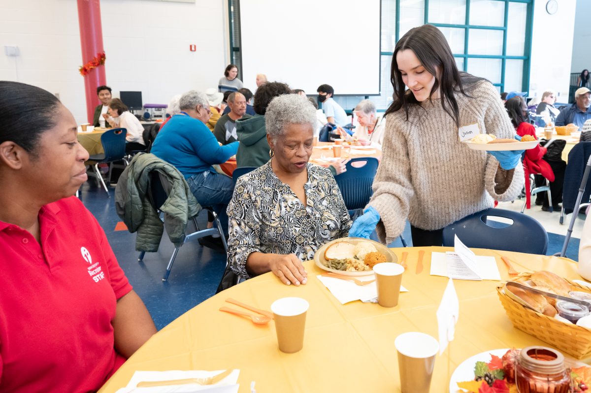 Junior Julin Marcelino-White serves food to a senior citizen at the schools 45th senior citizen luncheon. It was really nice to be able to host this event. Its a great gesture by the school, Key Club vice president Maya Zutsi said.