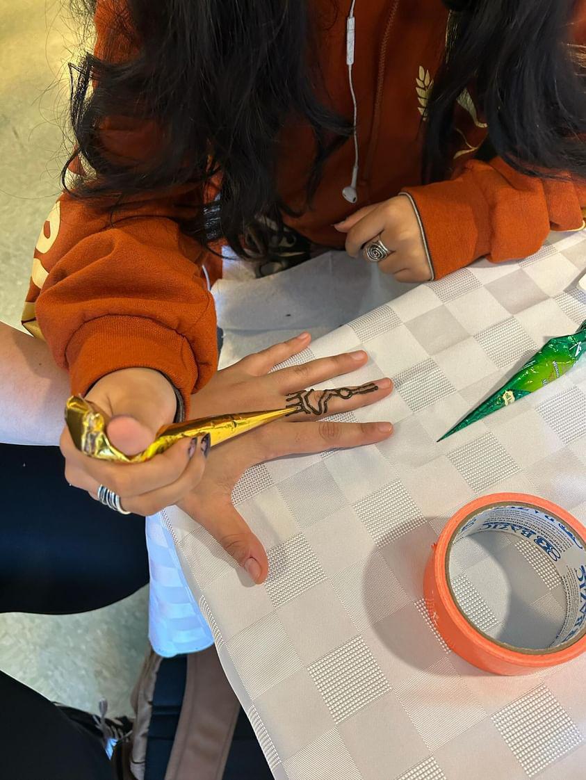 Sophomore Meher Singh draws a henna hand design as a part of the fundraiser. Along with hand designs, the clubs also put on a bake sale to raise the most money possible.