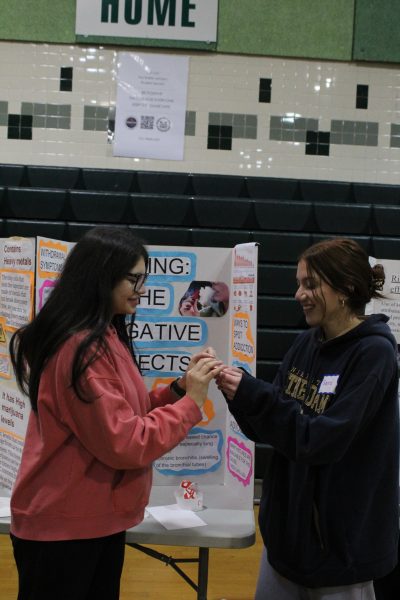 Sophomore Gianna Granados shows sophomore Stephanie Ramirez her poster while handing her a sticker. “I chose this topic because vaping is something very common among teenagers and we should not do it, Granados said.