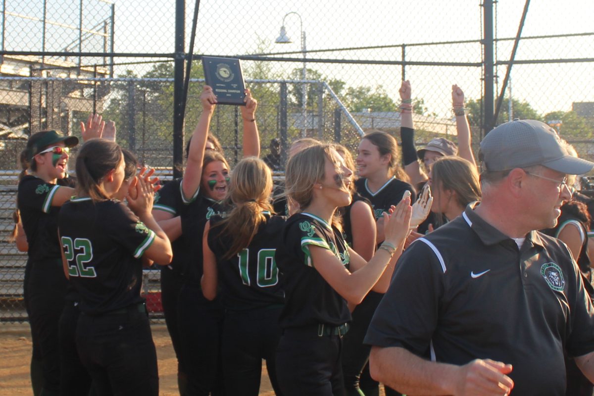 Team captain and starting pitcher Sami Rosenberg lifts the region champion plaque over her head as teammates celebrate. WJ softball won its region in 2023, a feat the team hopes to repeat this year.