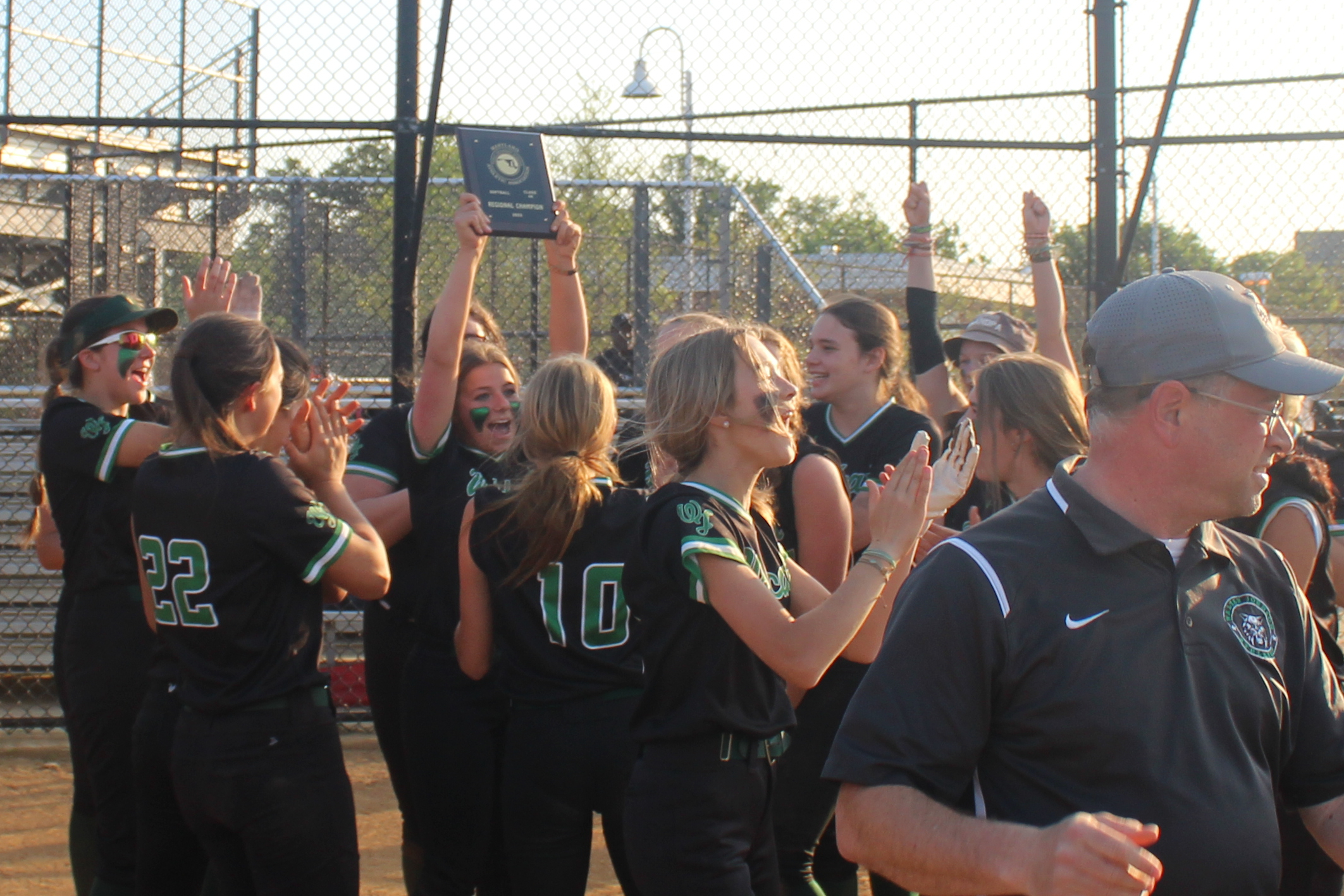 Team captain and starting pitcher Sami Rosenberg lifts the region champion plaque over her head as teammates celebrate. WJ softball won its region in 2023, a feat the team hopes to repeat this year.