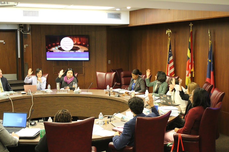 MCPS Board of Education members raise their hands in favor of delaying construction at Woodward and Crown High Schools. The plan specifically calls for delaying auditoriums at both schools until funds are appropriated for their construction.  