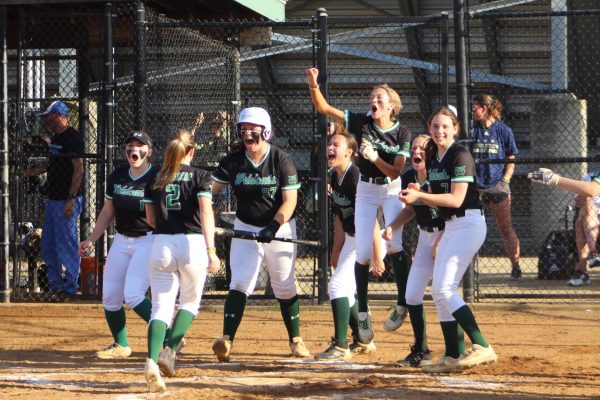 The softball team celebrates and awaits as senior Carly Gilder rounds the bases after hitting a home run. Gilders home run was the first hit she had gotten off of Churchill pitcher Maggie King in nine attempts and sealed the victory for the Wildcats in the regional semifinal.